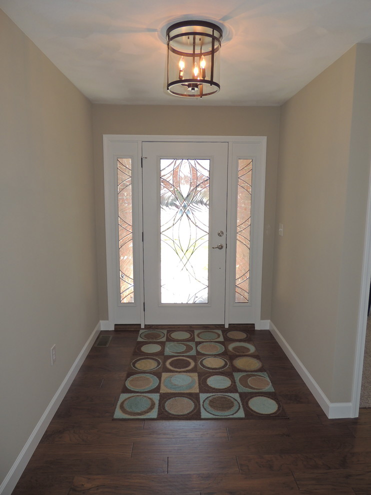 Foto di una porta d'ingresso chic di medie dimensioni con pareti beige, pavimento in legno massello medio, una porta singola e una porta in vetro