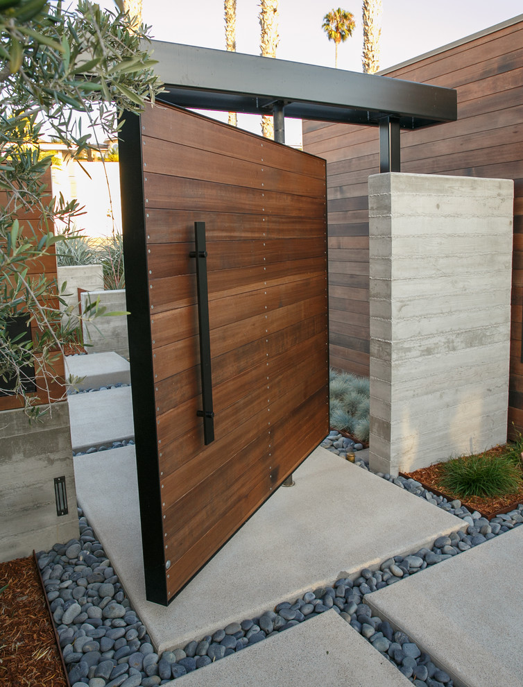 Exempel på en mellanstor modern ingång och ytterdörr, med betonggolv, en pivotdörr och mellanmörk trädörr
