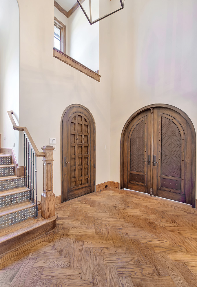 Diseño de puerta principal rural con paredes beige, suelo de madera en tonos medios, puerta simple y puerta de madera oscura