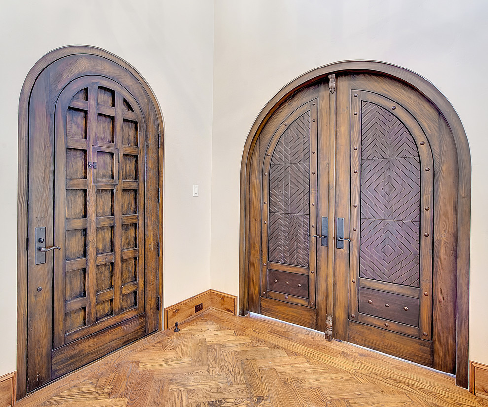 Cette image montre une porte d'entrée chalet avec un mur beige, un sol en bois brun, une porte simple et une porte en bois foncé.