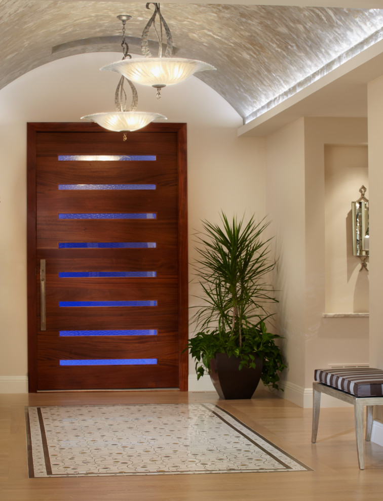 Réalisation d'une entrée design avec un mur beige, parquet clair, une porte pivot et une porte en bois foncé.