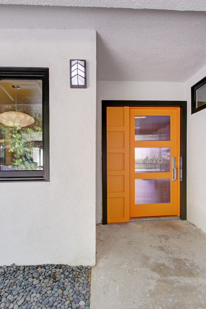 Esempio di una porta d'ingresso minimalista con pareti bianche, pavimento in cemento, una porta singola e una porta arancione