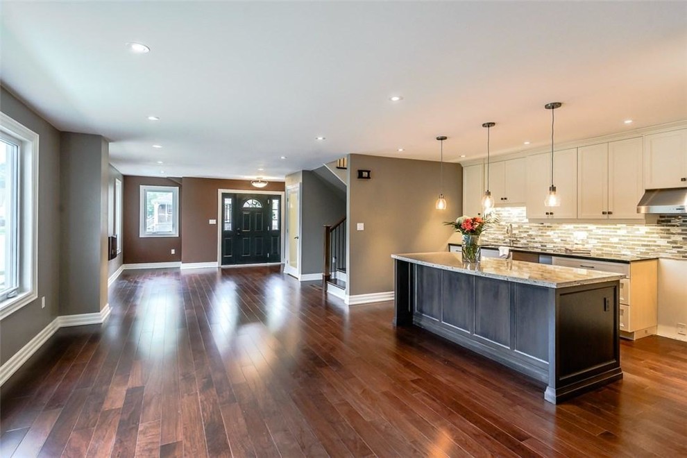This is an example of an expansive modern foyer in Other with medium hardwood flooring, a single front door, a black front door, brown floors and beige walls.