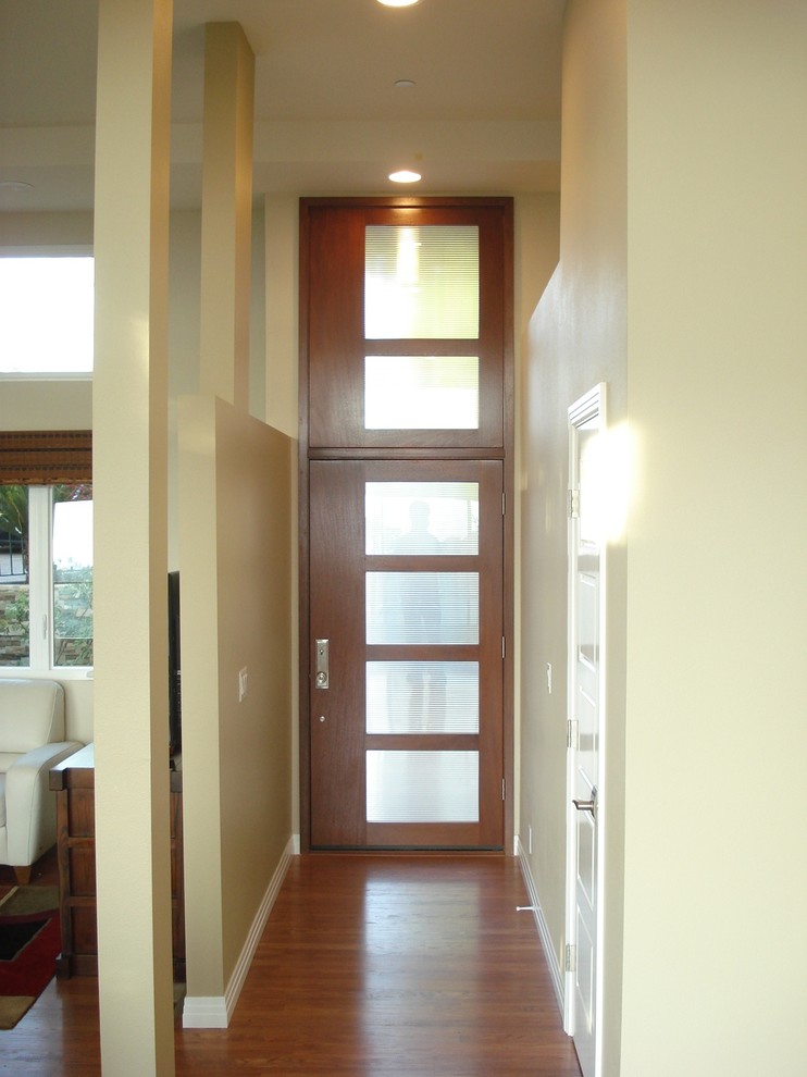 Bild på en mellanstor funkis ingång och ytterdörr, med beige väggar, mellanmörkt trägolv, en enkeldörr, mellanmörk trädörr och brunt golv