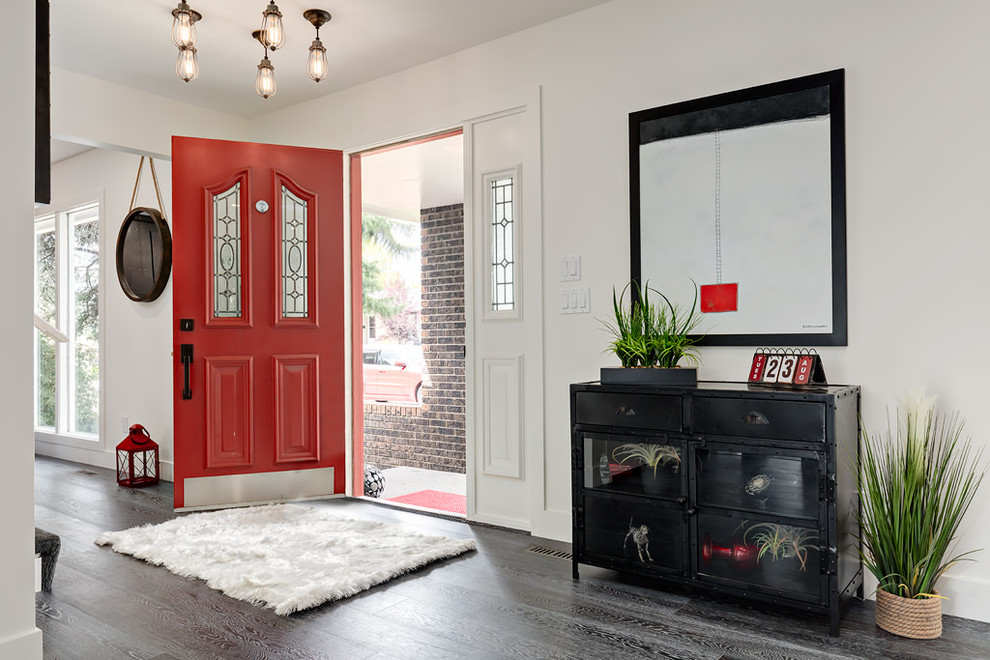 Inredning av en klassisk mellanstor ingång och ytterdörr, med vita väggar, mörkt trägolv, en enkeldörr och en röd dörr