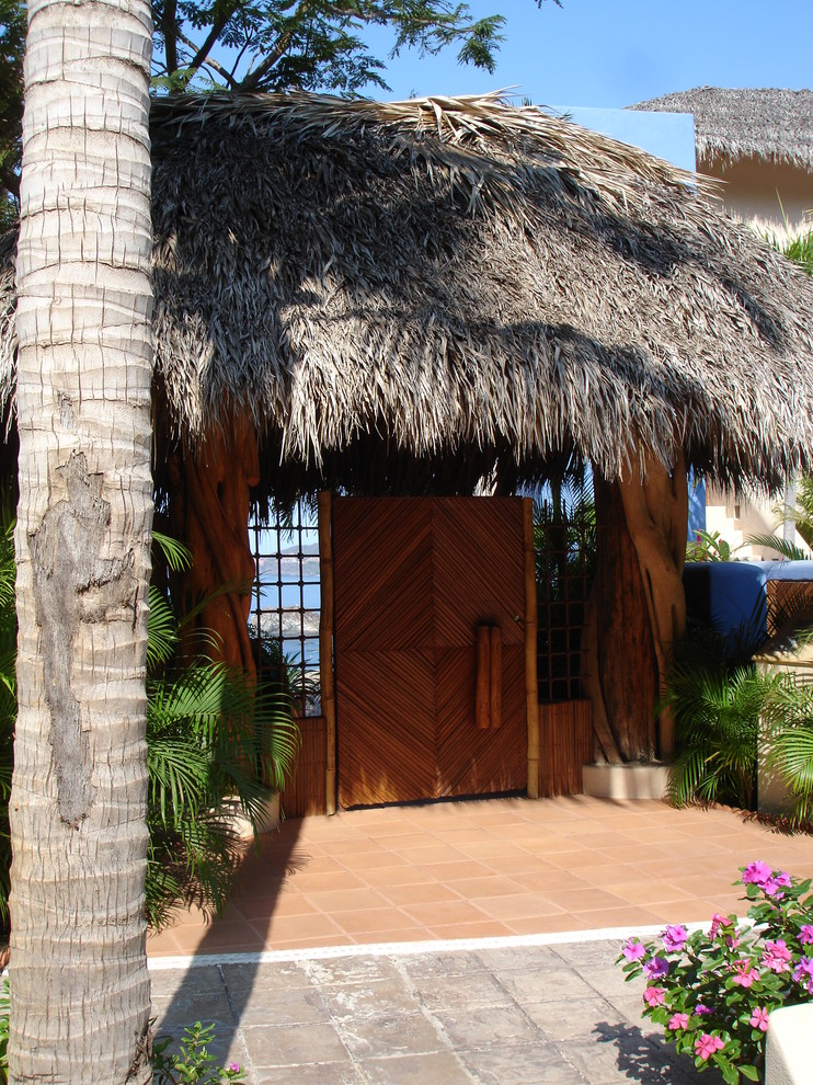 Diseño de puerta principal tropical con puerta simple y puerta de madera en tonos medios