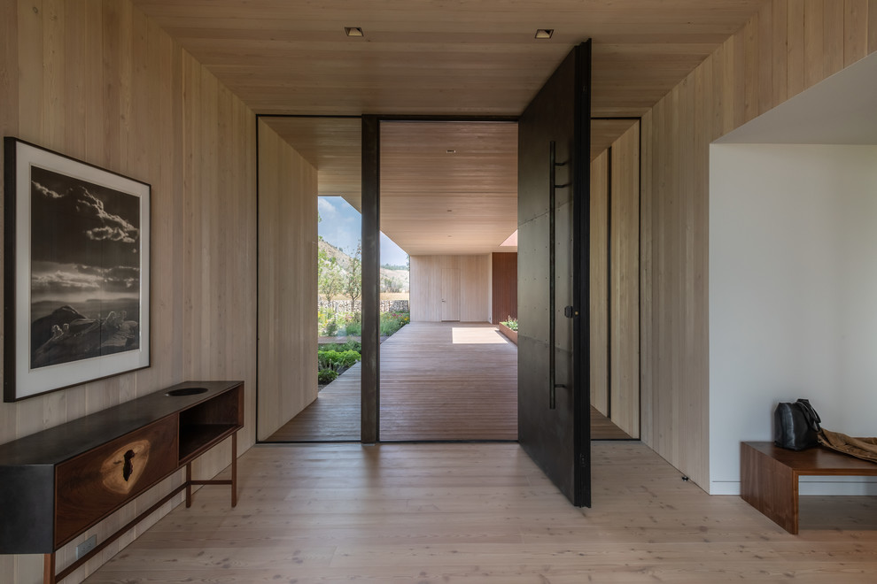 Diseño de entrada rústica con paredes blancas, suelo de madera clara, puerta pivotante, puerta negra y suelo beige