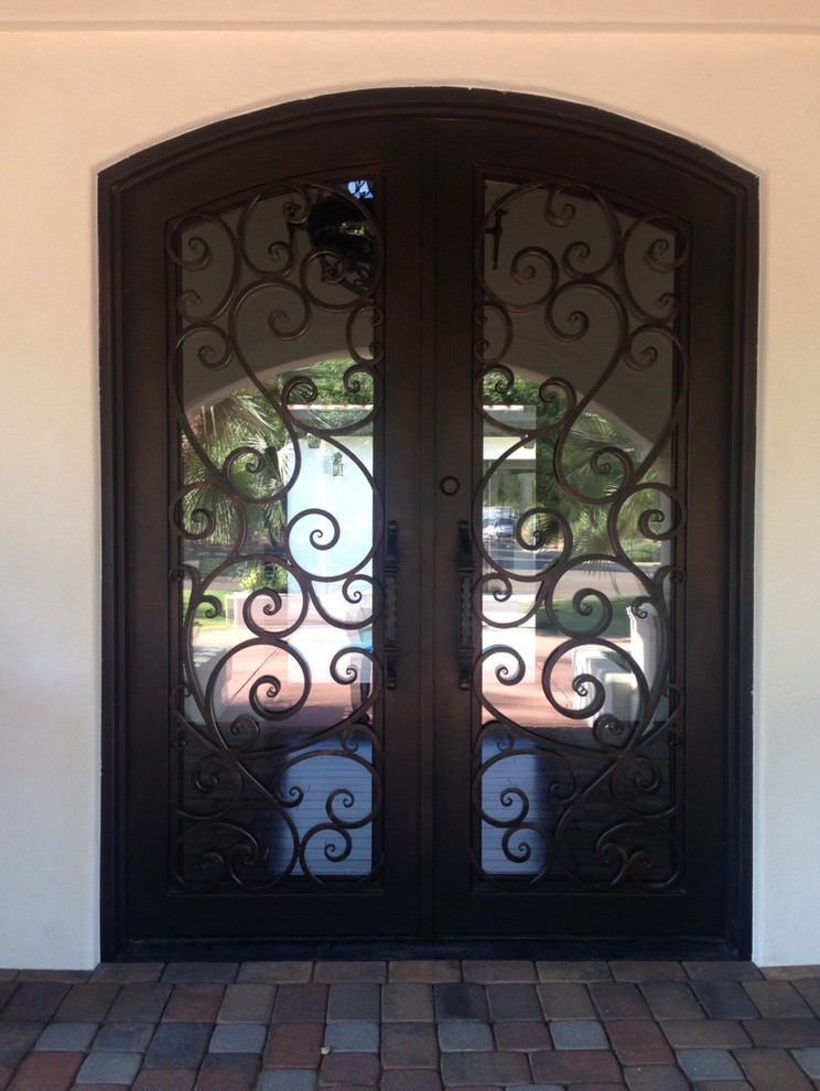Modelo de puerta principal mediterránea de tamaño medio con paredes blancas, suelo de ladrillo, puerta doble y puerta de vidrio