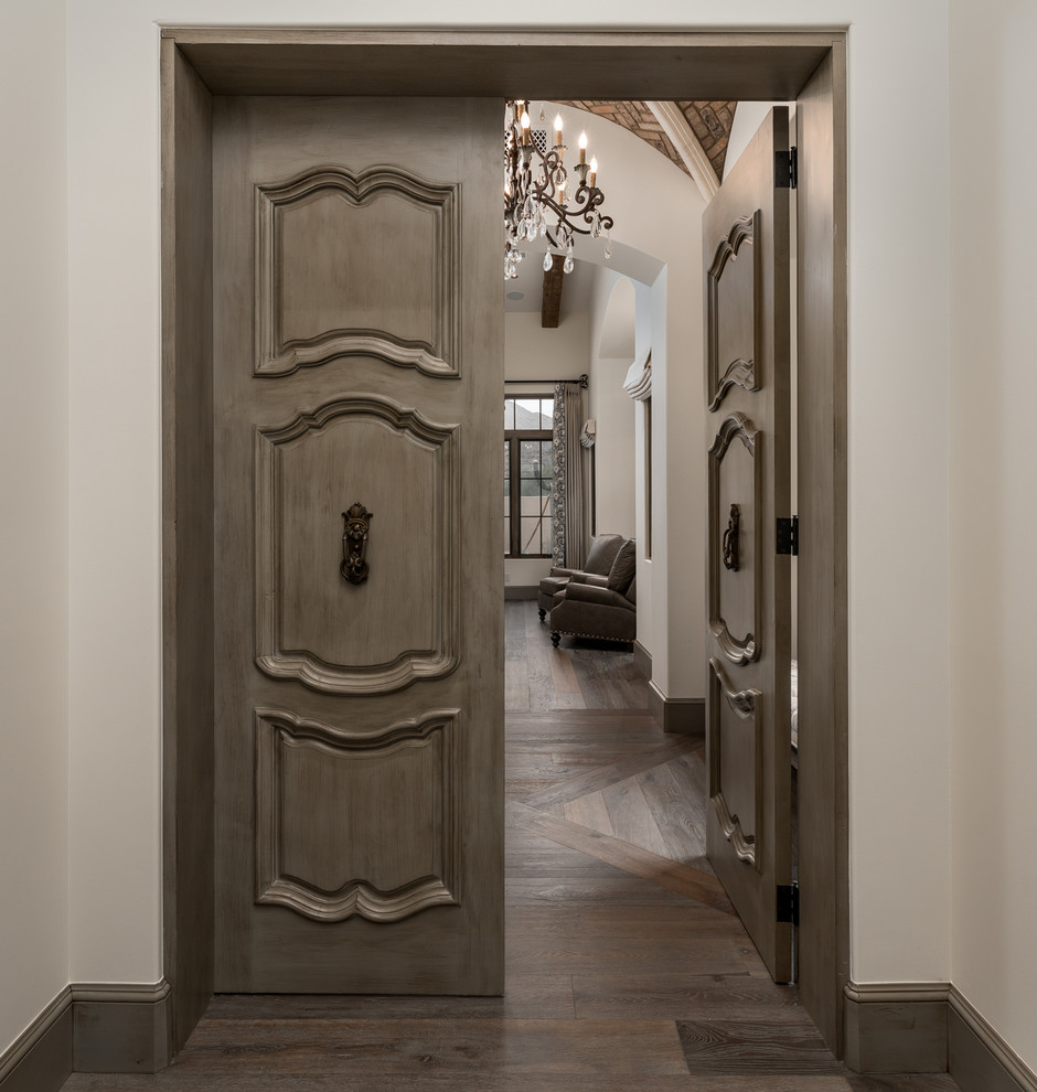 This is an example of a mediterranean entrance in Phoenix with a double front door, a brown front door, beige walls, medium hardwood flooring, brown floors, a vaulted ceiling and brick walls.