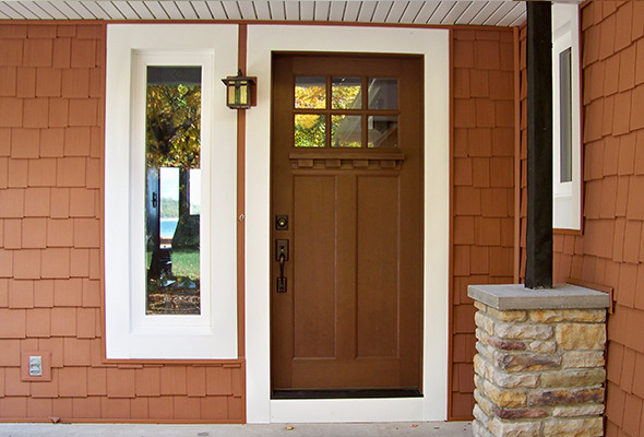 Aménagement d'une porte d'entrée craftsman de taille moyenne avec un mur orange, sol en béton ciré, une porte simple et une porte en bois foncé.