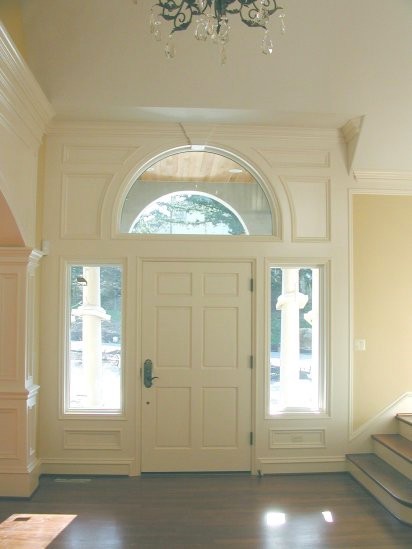 Inredning av en klassisk mellanstor ingång och ytterdörr, med beige väggar, mörkt trägolv, en enkeldörr och en vit dörr
