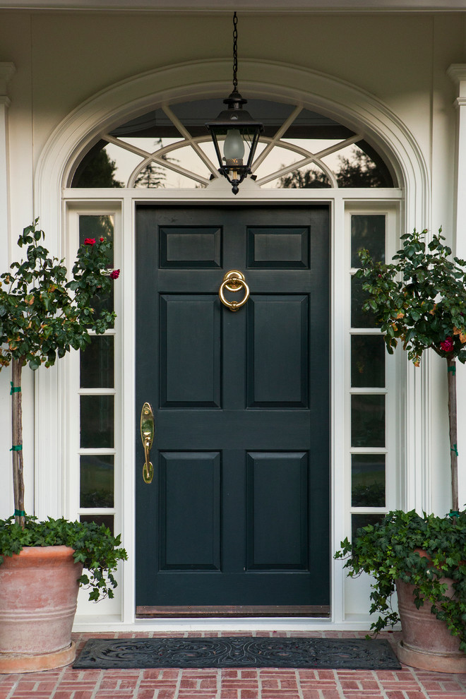 Пример оригинального дизайна: огромная входная дверь в классическом стиле с белыми стенами, кирпичным полом, одностворчатой входной дверью и черной входной дверью