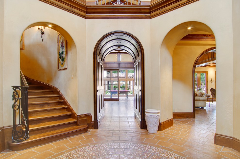 Photo of a large mediterranean foyer in San Francisco with beige walls, terracotta flooring and a medium wood front door.