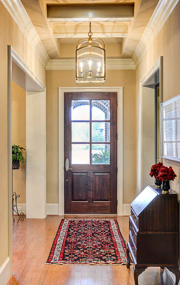 Idées déco pour un hall d'entrée classique de taille moyenne avec un mur beige, un sol en bois brun, une porte simple et une porte marron.
