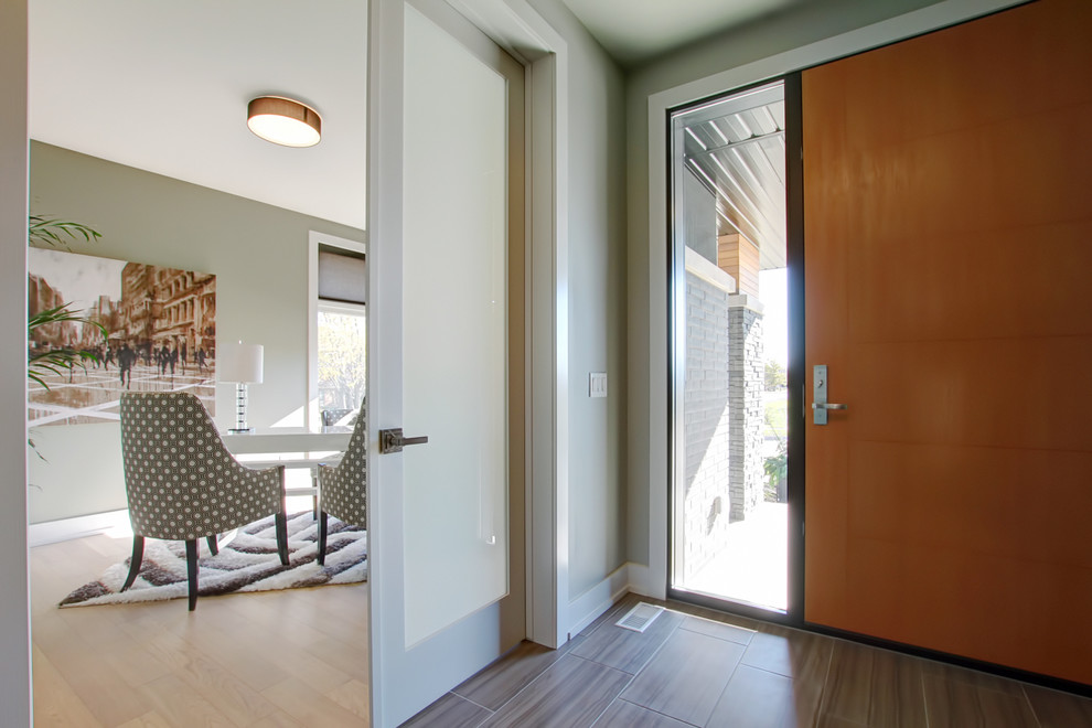 Foto de hall contemporáneo de tamaño medio con paredes beige, suelo de madera oscura, puerta simple, puerta de madera clara y suelo marrón