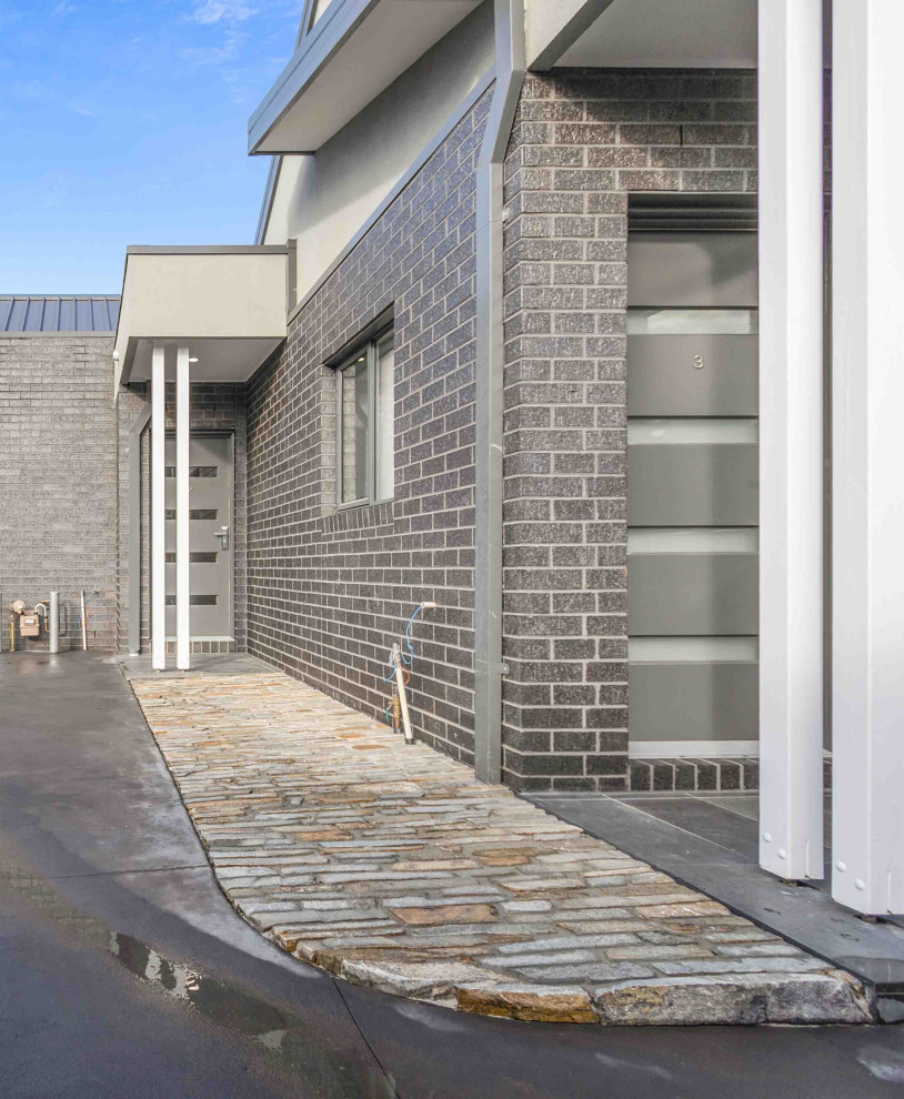 Kleine Moderne Haustür mit metallicfarbenen Wänden, Granitboden, Einzeltür, grauer Haustür, grauem Boden, gewölbter Decke und Ziegelwänden in Melbourne