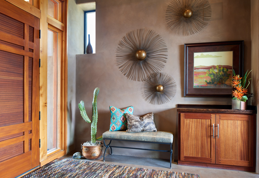 デンバーにあるサンタフェスタイルのおしゃれな玄関 (木目調のドア、グレーの床、茶色い壁) の写真