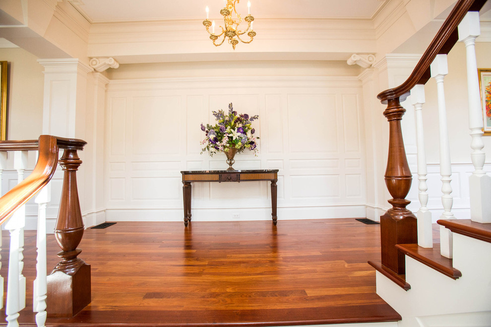 Foto de entrada clásica con paredes blancas y suelo de madera en tonos medios