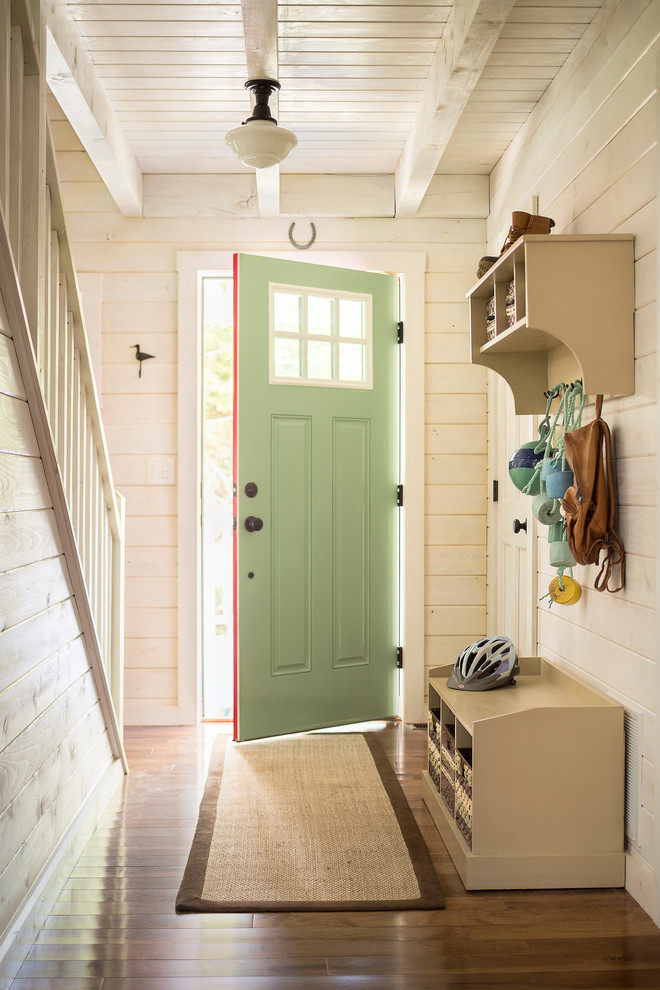 Modelo de puerta principal costera con paredes beige, suelo de madera en tonos medios, puerta simple y puerta verde