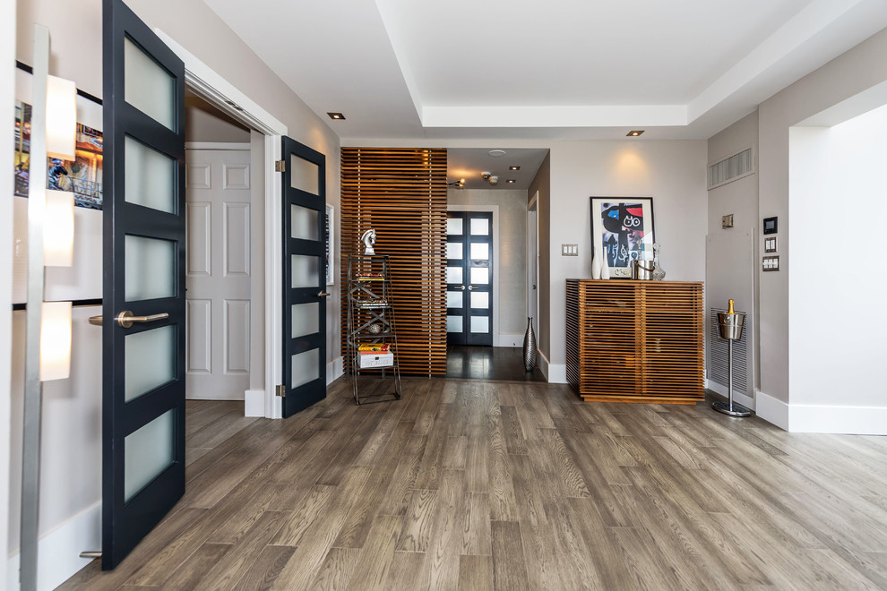 This is an example of a contemporary front door in Toronto with grey walls, ceramic flooring, a dark wood front door and brown floors.