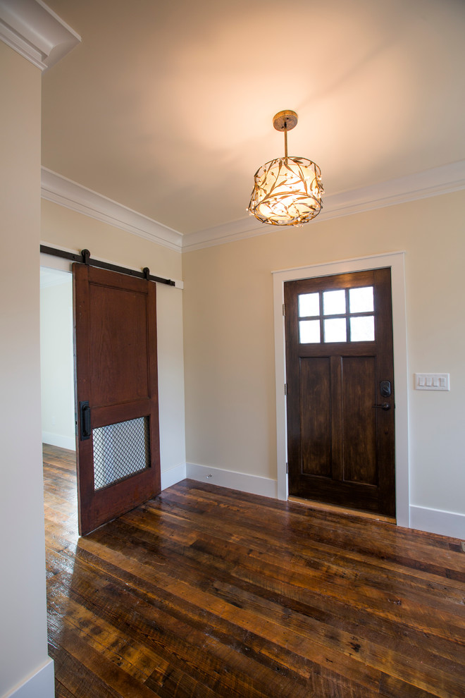 Ejemplo de distribuidor de estilo americano de tamaño medio con paredes beige, suelo de madera oscura, puerta simple, puerta de madera oscura y suelo marrón
