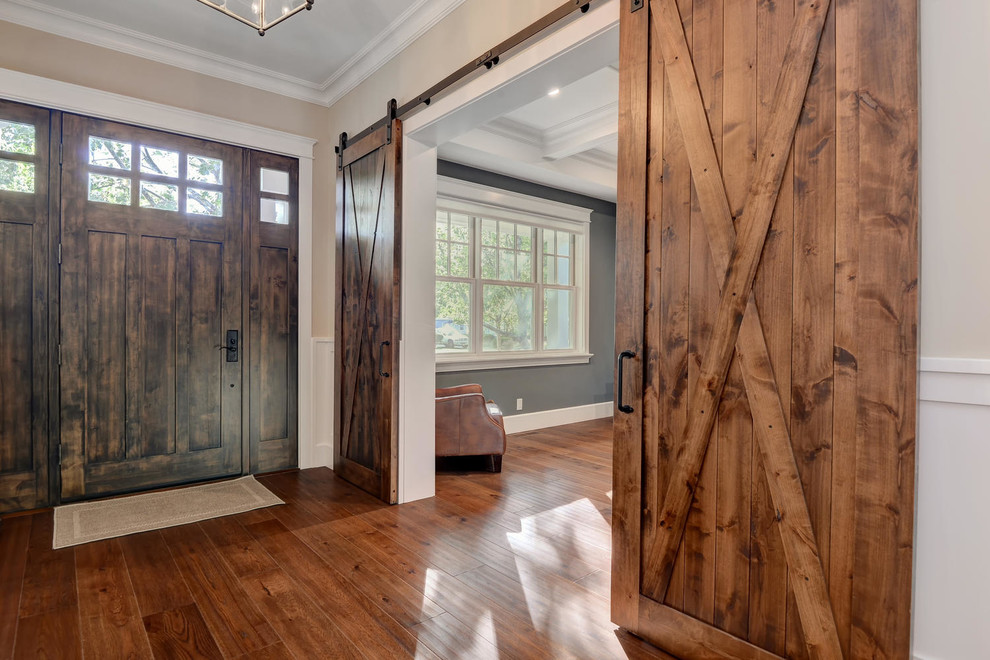 Cette image montre un hall d'entrée traditionnel de taille moyenne avec un sol en bois brun, une porte simple, une porte en bois foncé et un sol marron.