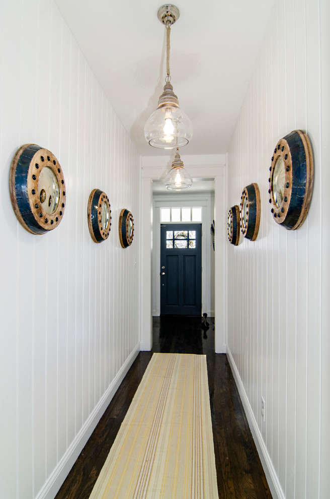 Diseño de hall marinero con paredes blancas, suelo de madera oscura, puerta simple y puerta negra