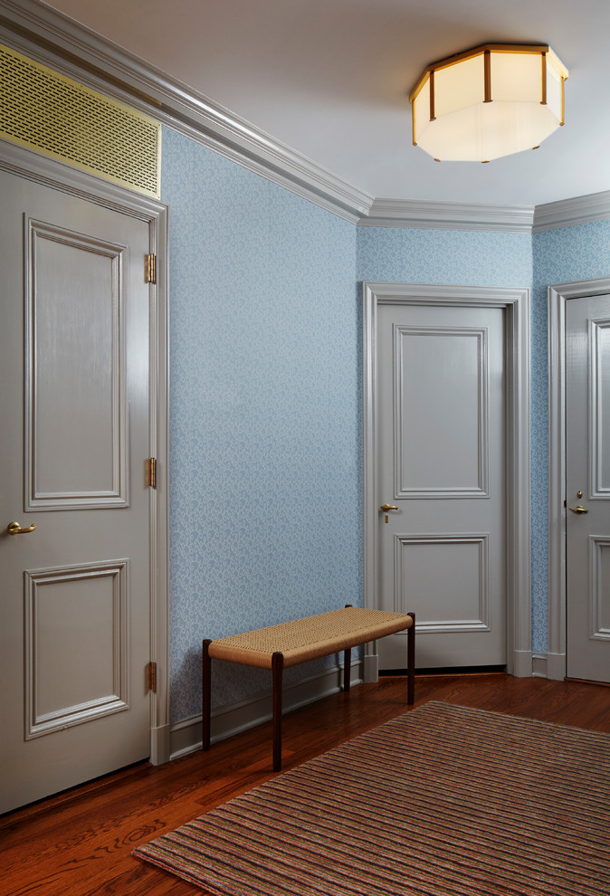 Inspiration pour un petit hall d'entrée traditionnel avec un mur bleu, un sol en bois brun et une porte grise.
