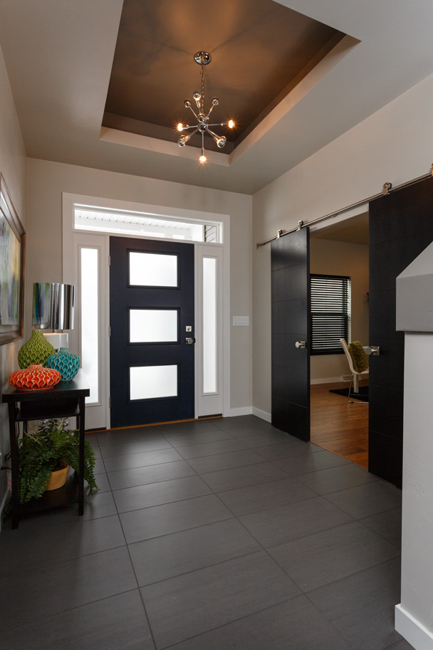 Foto di un grande ingresso minimalista con pareti beige, pavimento in gres porcellanato, una porta singola, una porta nera e pavimento grigio