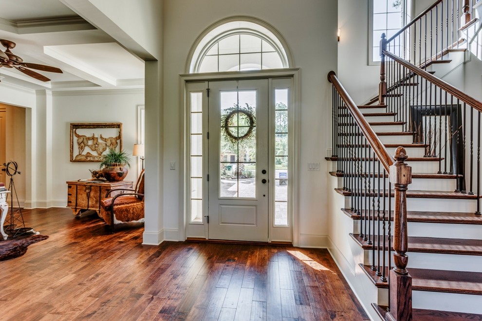 Example of a large tuscan medium tone wood floor and brown floor entryway design in Jacksonville with white walls and a white front door