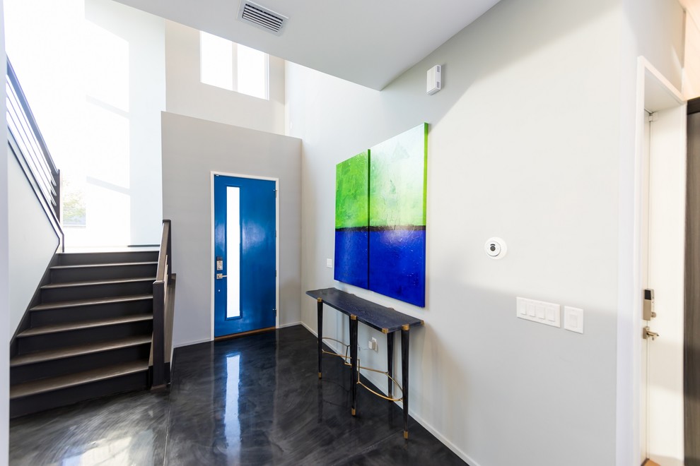 Esempio di un ingresso minimalista di medie dimensioni con pareti grigie, pavimento in cemento, una porta singola, una porta blu e pavimento grigio