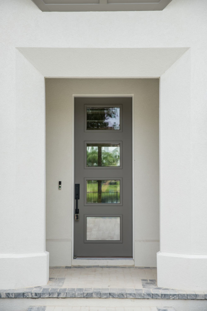 Пример оригинального дизайна: большая входная дверь в стиле неоклассика (современная классика) с белыми стенами, кирпичным полом, одностворчатой входной дверью, серой входной дверью, белым полом и деревянным потолком