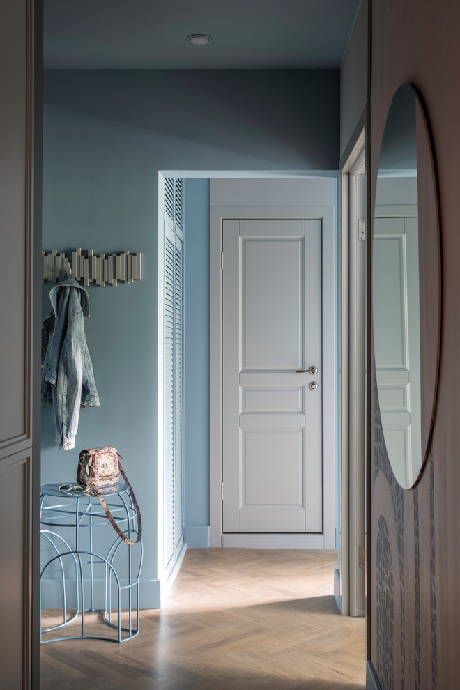 На фото: маленькая узкая прихожая в современном стиле с синими стенами, светлым паркетным полом, одностворчатой входной дверью, белой входной дверью и коричневым полом для на участке и в саду