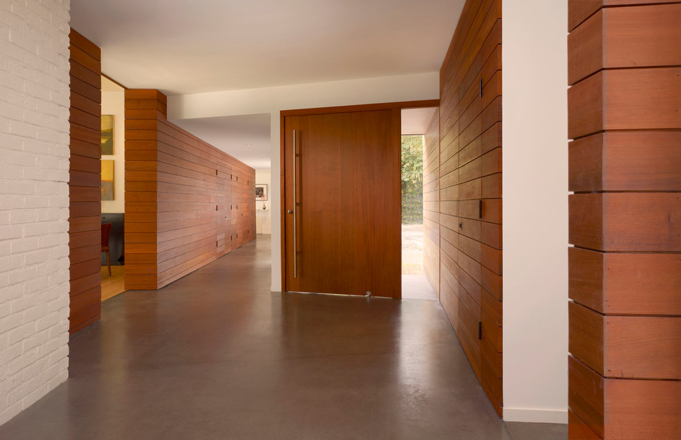 Пример оригинального дизайна: большое фойе в стиле модернизм с бетонным полом, одностворчатой входной дверью, входной дверью из дерева среднего тона и коричневыми стенами