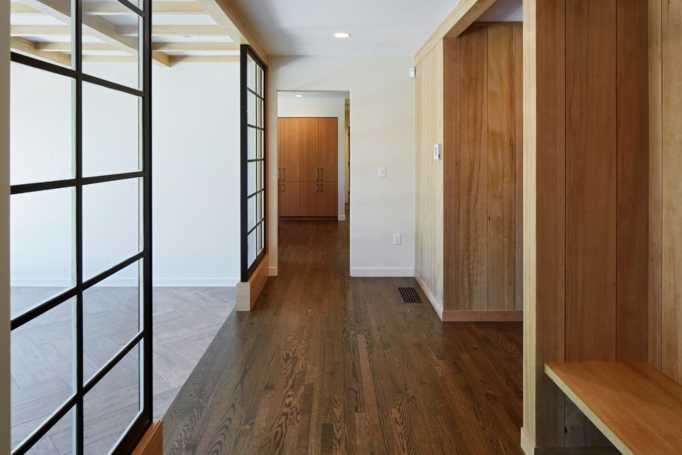 Exemple d'une entrée rétro avec un mur blanc, un sol en bois brun, une porte simple, une porte noire et un sol marron.