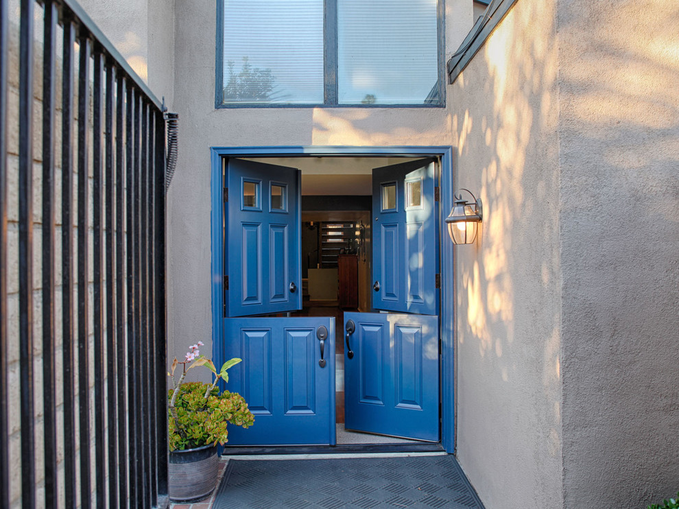 Inredning av en klassisk stor ingång och ytterdörr, med bruna väggar, en tvådelad stalldörr och en blå dörr