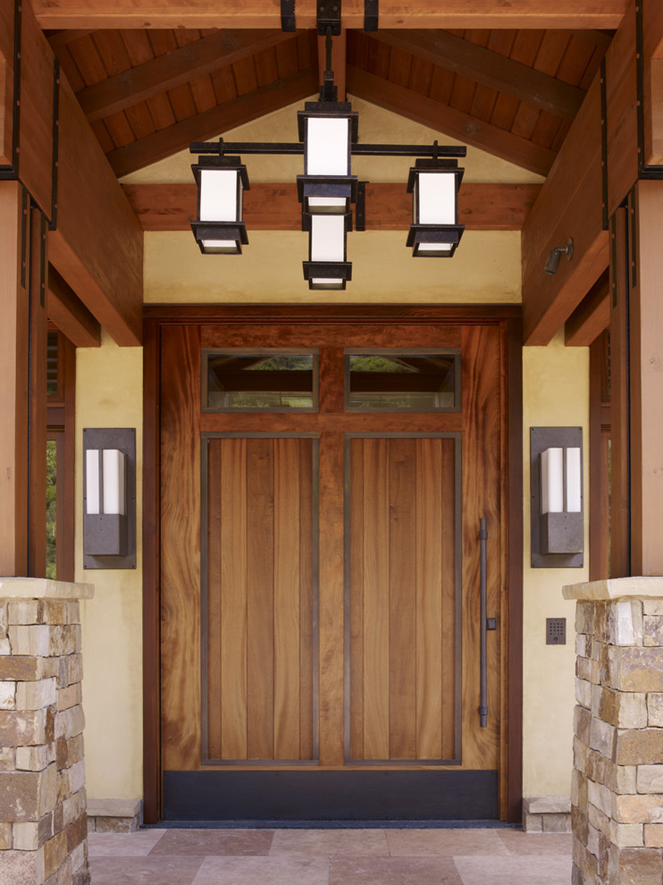 Идея дизайна: входная дверь в современном стиле с входной дверью из дерева среднего тона, бежевыми стенами, полом из известняка, поворотной входной дверью и бежевым полом