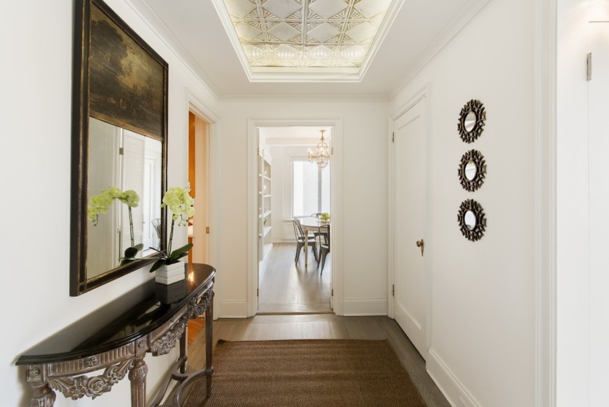 Ispirazione per un corridoio contemporaneo di medie dimensioni con pareti bianche, parquet chiaro, una porta singola, una porta bianca e pavimento beige