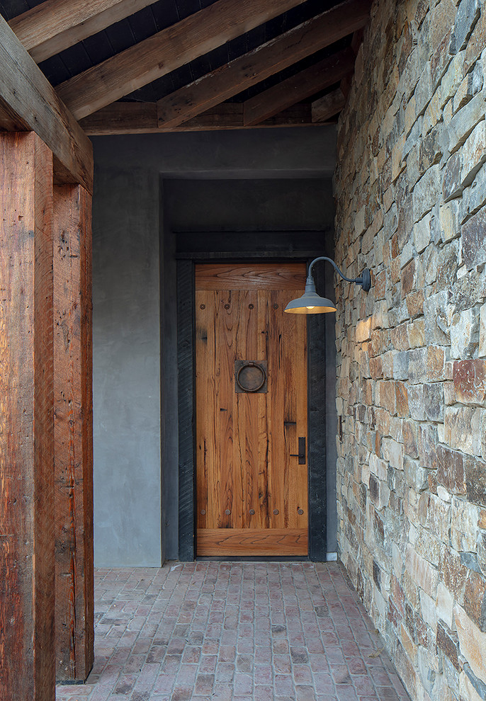 Пример оригинального дизайна: входная дверь среднего размера в стиле рустика с серыми стенами, кирпичным полом, одностворчатой входной дверью и входной дверью из дерева среднего тона