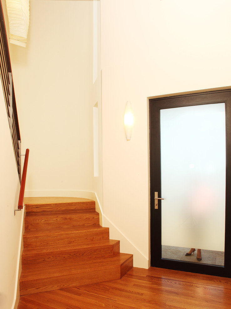 Esempio di una piccola porta d'ingresso contemporanea con una porta in vetro, pareti bianche, pavimento in legno massello medio e una porta singola