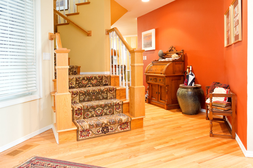 This is an example of a large traditional foyer in Boise with orange walls, medium hardwood flooring, a single front door, a black front door and brown floors.