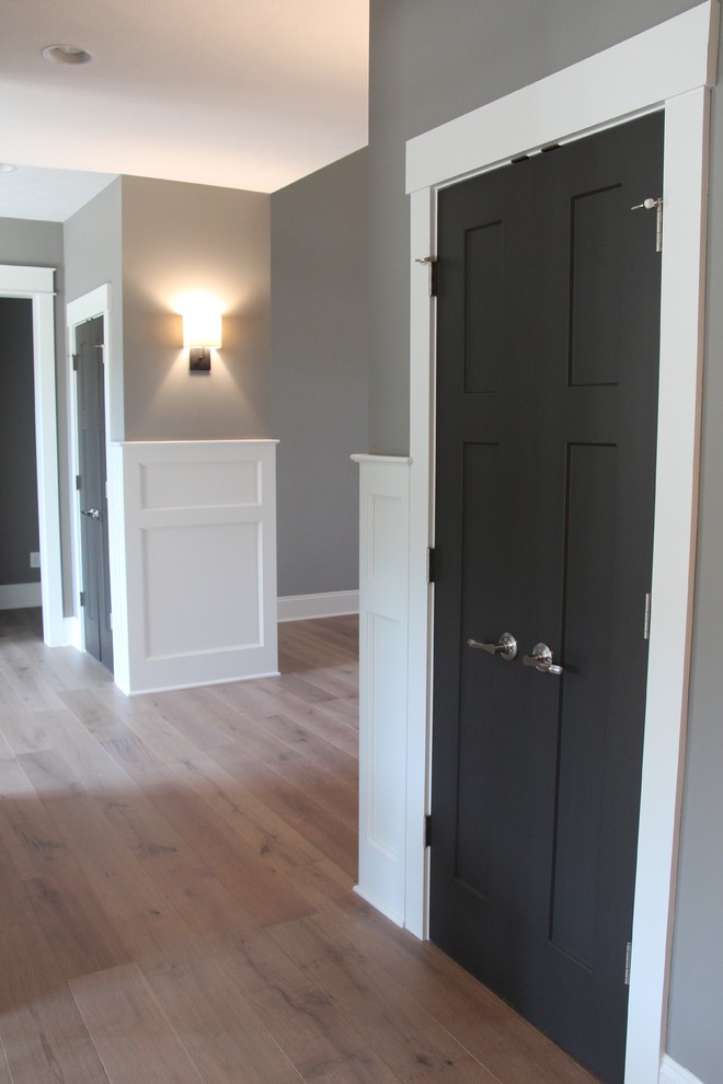 Ispirazione per un ingresso minimalista di medie dimensioni con pareti grigie, pavimento in legno massello medio, una porta singola e una porta nera