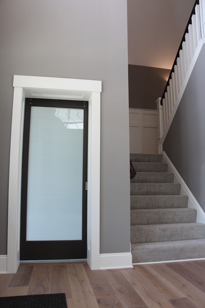 Foto di un ingresso minimalista di medie dimensioni con pareti grigie, pavimento in legno massello medio, una porta singola e una porta nera