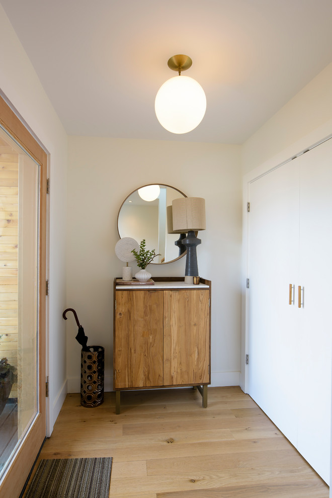 Ejemplo de distribuidor nórdico de tamaño medio con paredes blancas, suelo de madera clara, puerta simple y puerta de madera en tonos medios