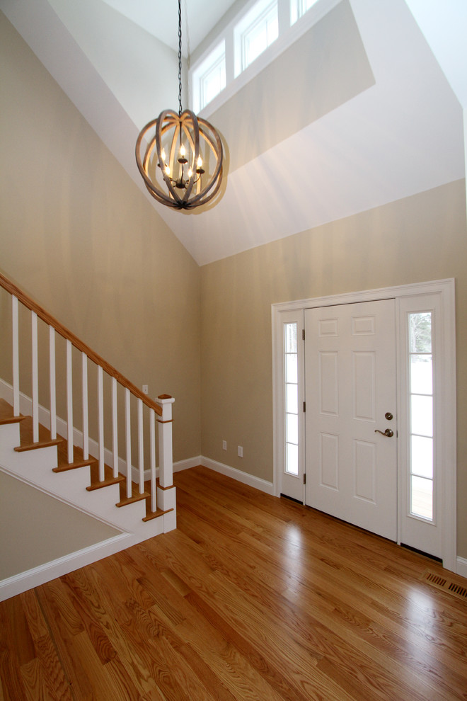 Idée de décoration pour un hall d'entrée design de taille moyenne avec un sol en bois brun, une porte simple et une porte blanche.