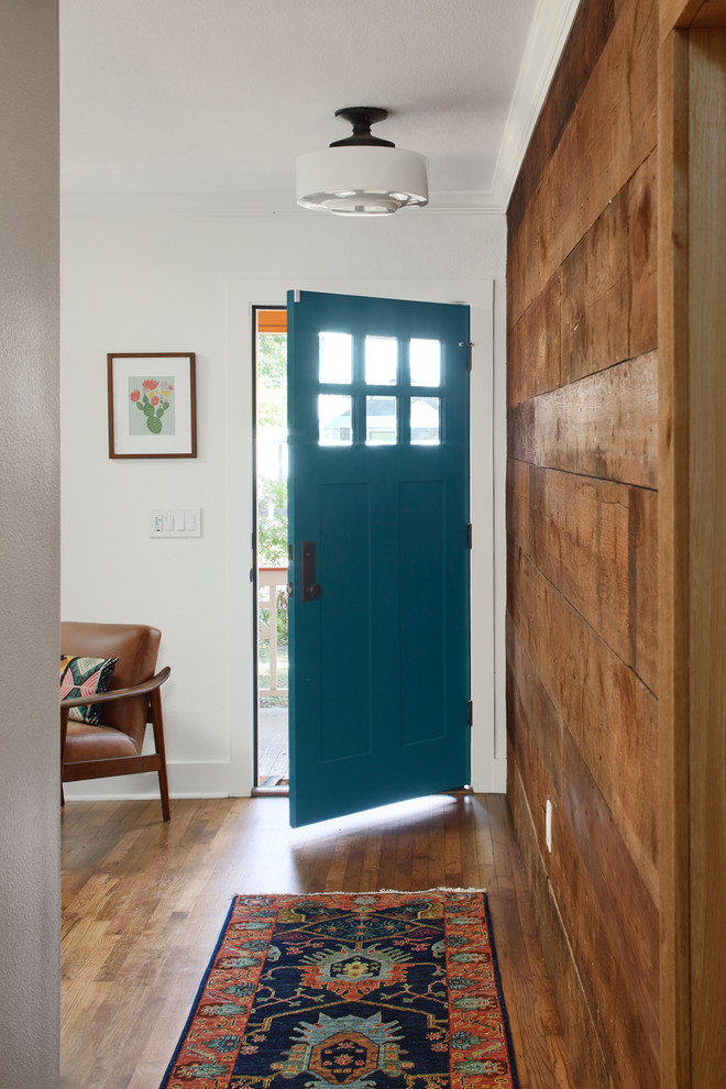 Modelo de puerta principal bohemia de tamaño medio con paredes blancas, suelo de madera en tonos medios, puerta simple, puerta azul y suelo marrón