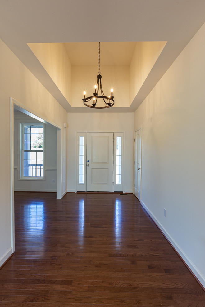 Inspiration pour un hall d'entrée traditionnel de taille moyenne avec un mur blanc, parquet foncé, une porte simple, une porte blanche et un sol marron.