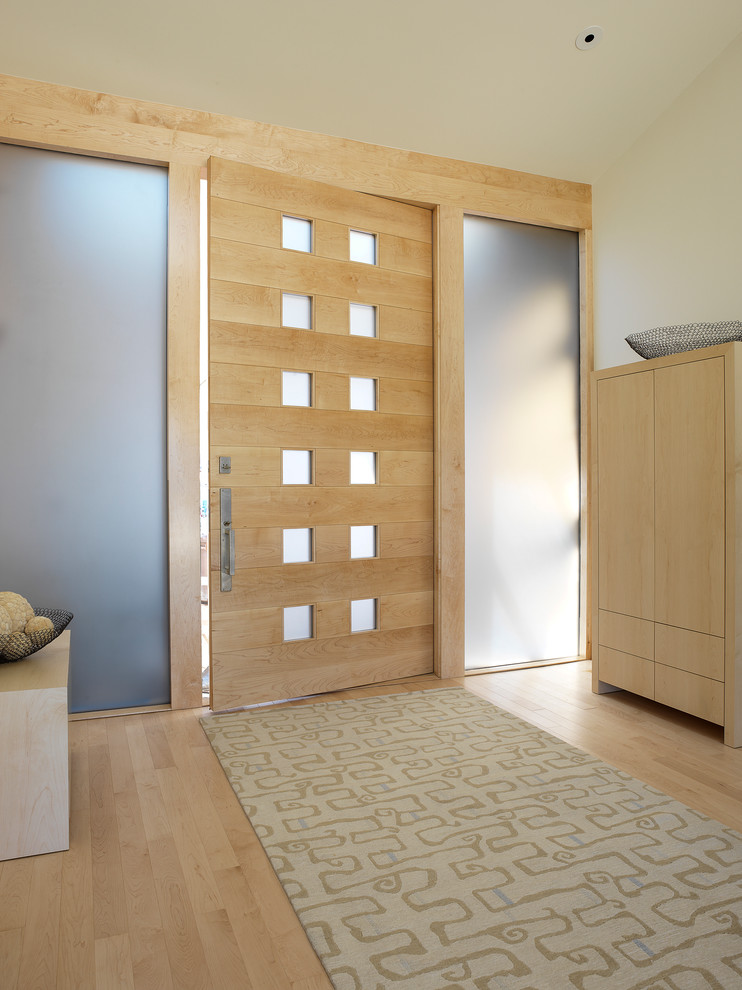 Foto de hall moderno con paredes blancas, suelo de madera clara, puerta simple y puerta de madera clara