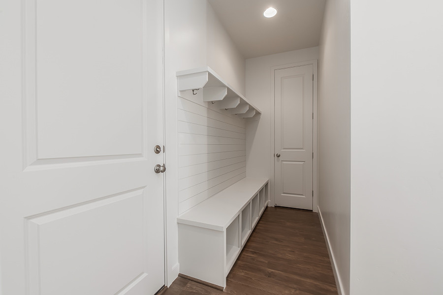 Idées déco pour une entrée contemporaine de taille moyenne avec un vestiaire, un mur blanc, sol en stratifié, une porte simple, une porte blanche et un sol marron.