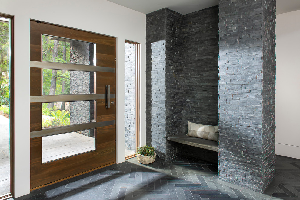 Cette photo montre un hall d'entrée tendance avec un mur blanc, une porte simple, une porte en bois foncé et un sol gris.